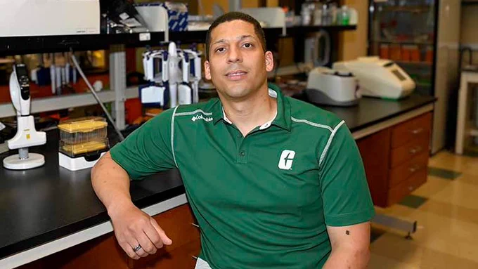 Augusto Danillo sits in a research lab where he is studying genetics.