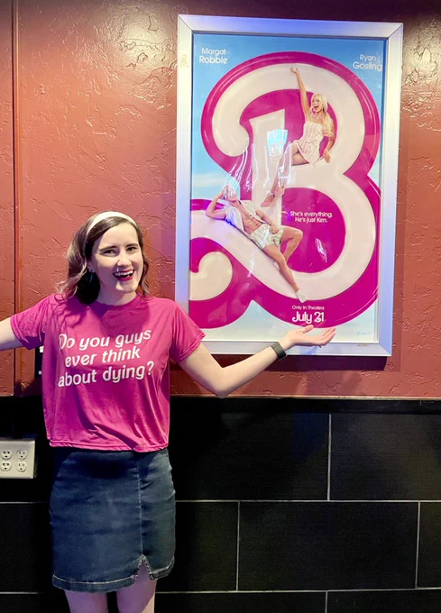 Emily wearing a pink shirt that says “do you guys ever think about dying”