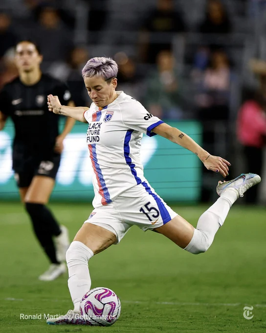 Soccer star Megan Rapinoe kicking a ball during a game.