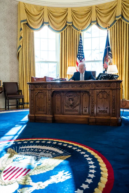 President Joe Biden works at the Resolute Desk in the Oval Office.