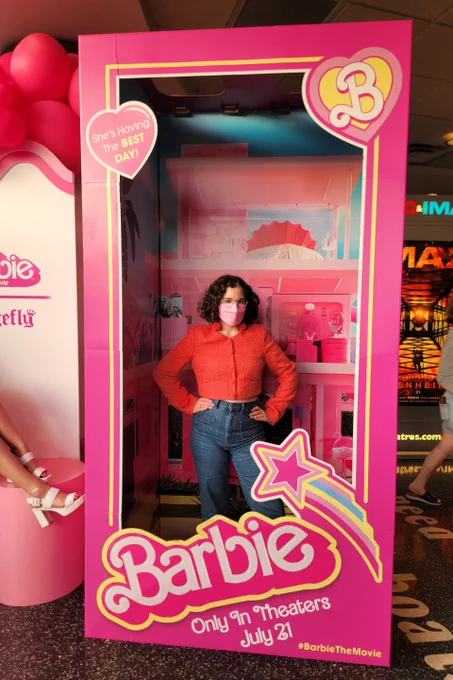 Sabrina poses in a Barbie box wearing q pink kn95 mask and a pink blazer