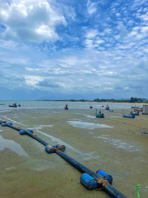Small fishing boats on a beach in Thailand while the tide is out. 