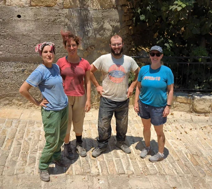 Four people covered in dirt standing on a cobble road