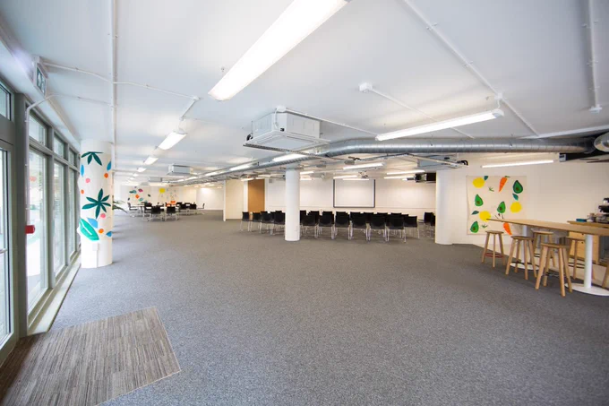 A wide angle picture of an event space, with empty tables and chairs in a large room.