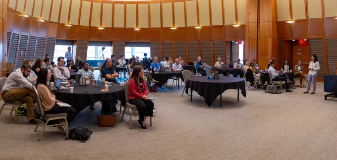 panorama of people sitting at tables watching presentation