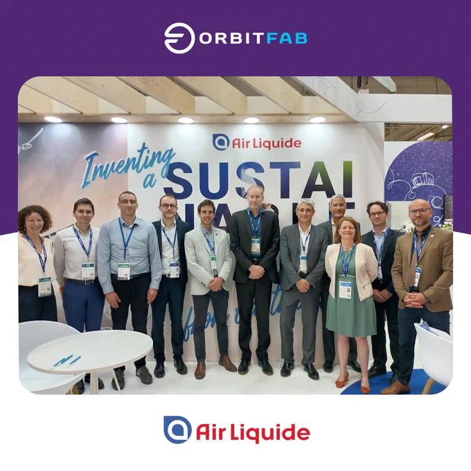 Orbit Fab's Daniel Faber and Seb Hill stand alongside AirLiquide's team in front of a sustainability wall mural