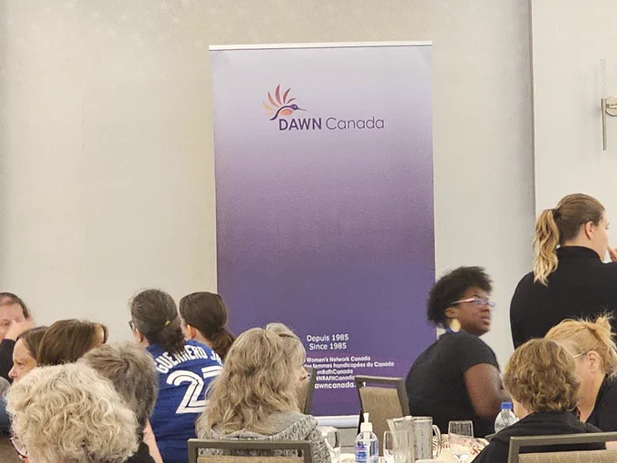 The DAWN Canada Popup  Banner on the stage with some attendees visible as folks return from break just prior to the DAWN presentation by our CEO