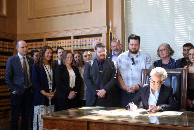 Governor Kotek signs bills relating to housing and homelessness as legislators and advocates look on.