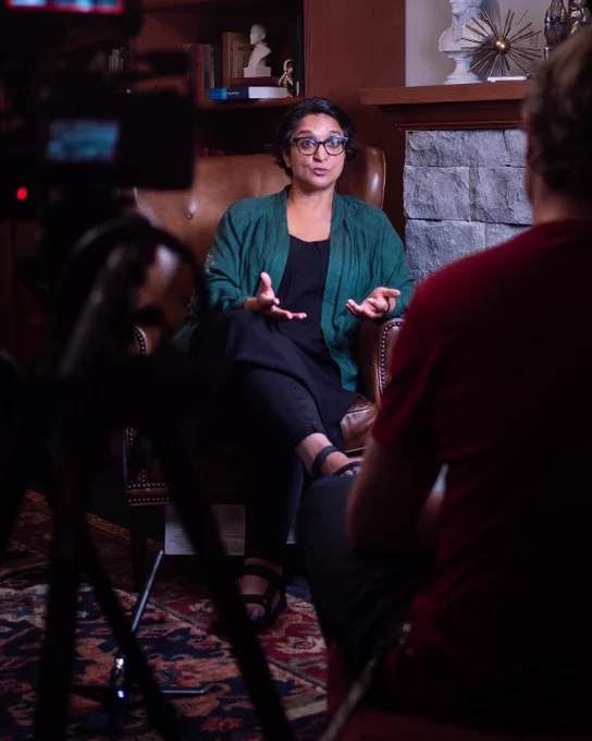 Photo of Amarjit Myers sitting in a lounge chair being interviewed