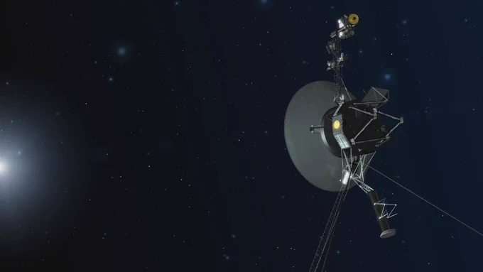 An illustration of Voyager as it travels through space. The Voyager spacecraft sits against a black background peppered with thousands of white dots representing distant stars. Voyager's white high-gain antenna dish, faces a glowing orb of white light as if it is traveling toward it. Other antenna and instruments surround the dish, fading into the darkness. 