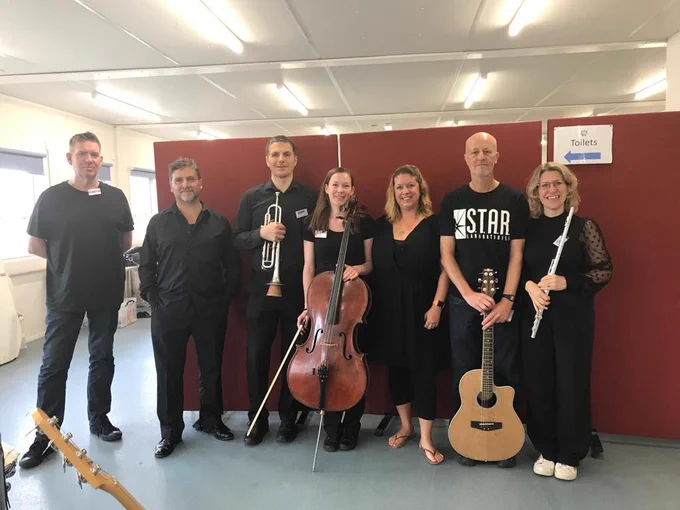 A small group of RPO musicians in black clothing posing for the camera with their instruments.