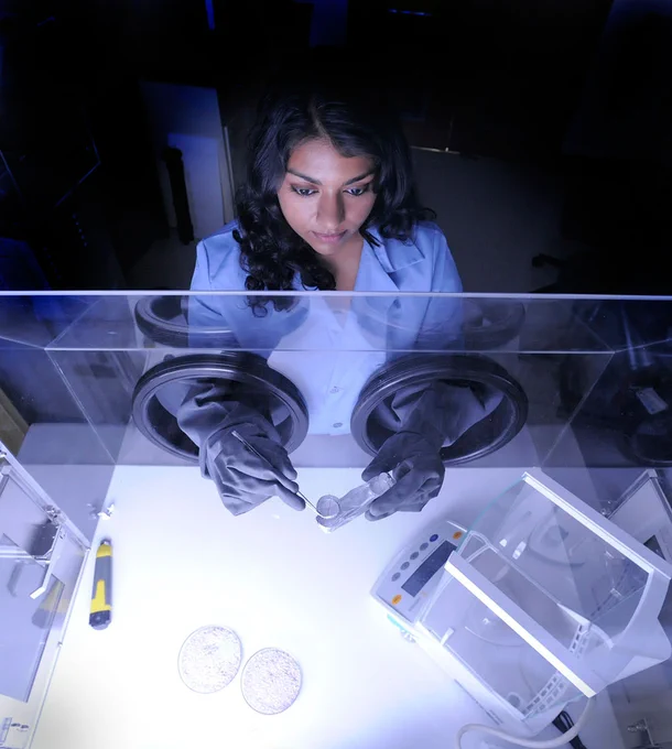 Former NASA intern and current NASA technologist Nithin Abraham uses sterile gloves in a clean container environment to study a simple sample in NASA’s Goddard Space Center’s laboratory. Wearing professional attire, she looks focused while using a small tweezer-like tool to interact with small science components. Credit: NASA/Pat Izzo