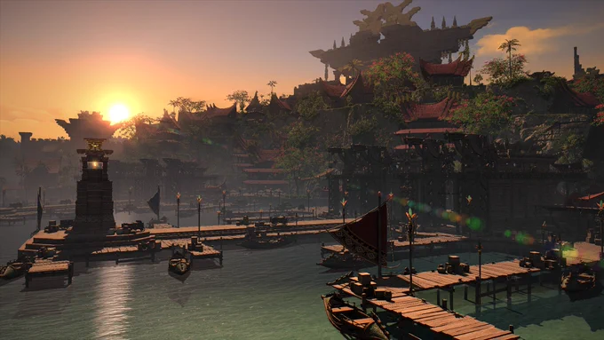 A screenshot of a port near the water, showing multiple wooden bridges with boats next to them. In the background are tall buildings with red roofs amongst trees covered with red flowers. In the distance is a large, tall structure towering over the buildings.