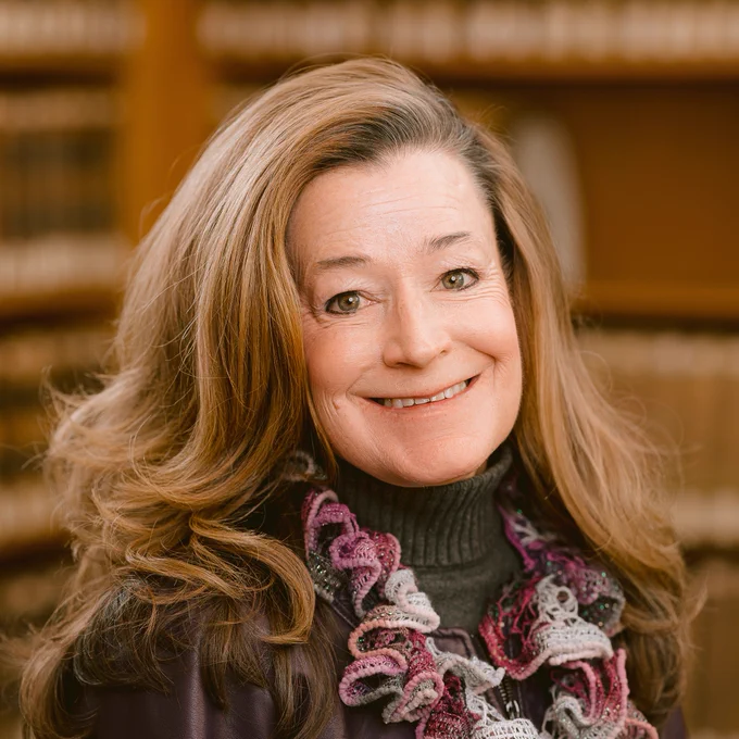 A headshot of Professor Schmitz smiling at the camera while standing in front of some bookshelves. 