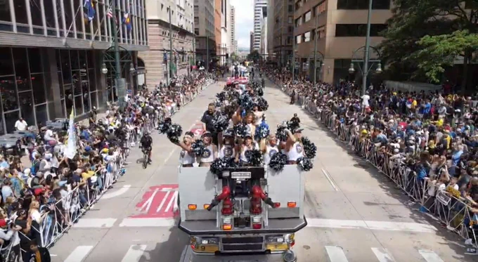 Nuggets cheerleaders on a firetruck among a crowded Denver street during the championship parade.