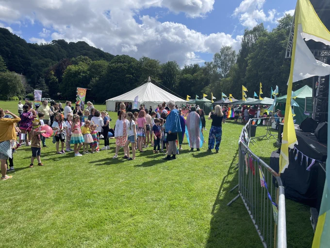 Sunshine, green grass, children wearing rainbow clothes, flags, joy