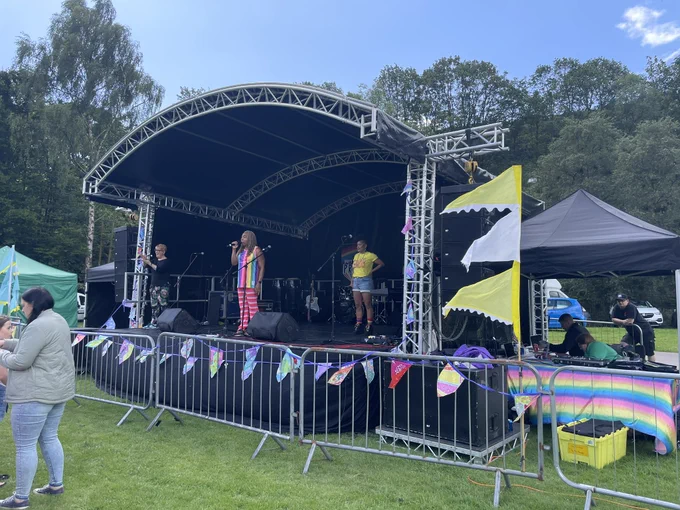 Ricky wearing a rainbow to and stripy trousers and Terry in a yellow happy valley pride T-shirt on stage
