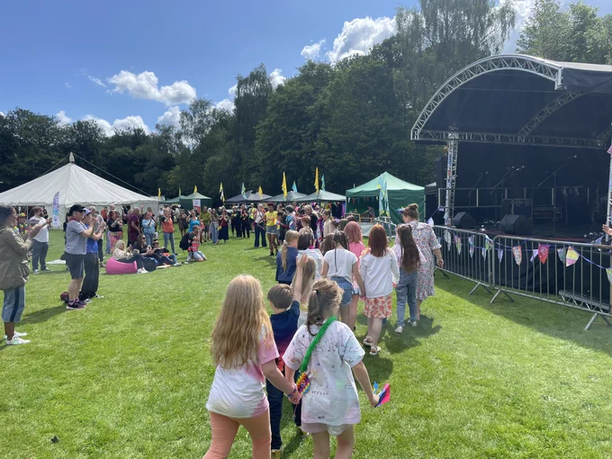 Sunshine, green grass, children wearing rainbow clothes, flags, joy