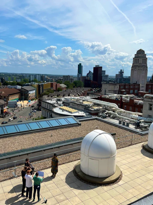 Film crew capturing  Khadijah Ibrahiim reciting poetry on the rooftop of the Bragg building at University of Leeds with a view across the Leeds skyline.