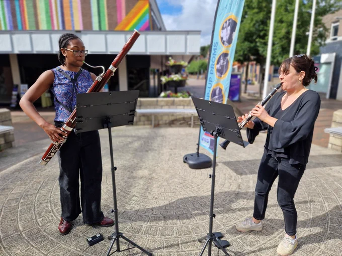 Two people playing musical instruments in the sunshine