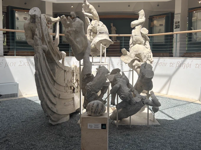 Scylla group, multiple figures all fragmented. Parts of ship on left with person hanging on the bow, Scylla’s hand grabbing odysseys head is displayed in the center, behind are two wolf heads of Scylla, on the right are fragments of what looks to be sailors struggling with Scylla’s tentacles