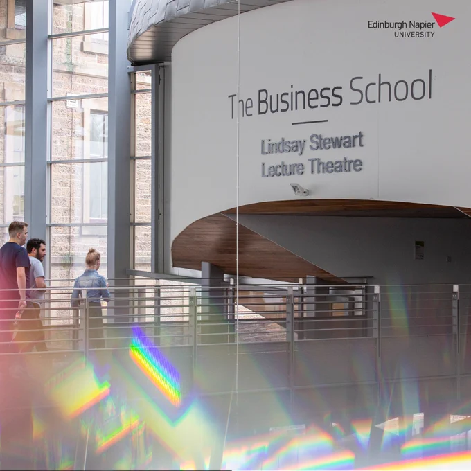 Students walking towards the entrance of Lindsay Stewart Lecture Theatre with signage above reading "The Business School - Lindsay Stewart Lecture Theatre".
