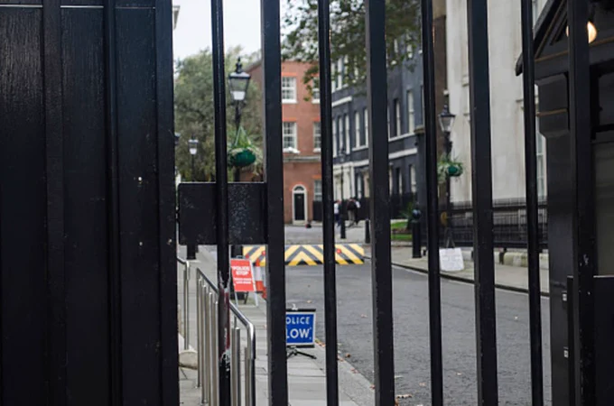 Picture through the gate at Downing Street, showing a “POLICE SLOW” sign and a security barrier in the road