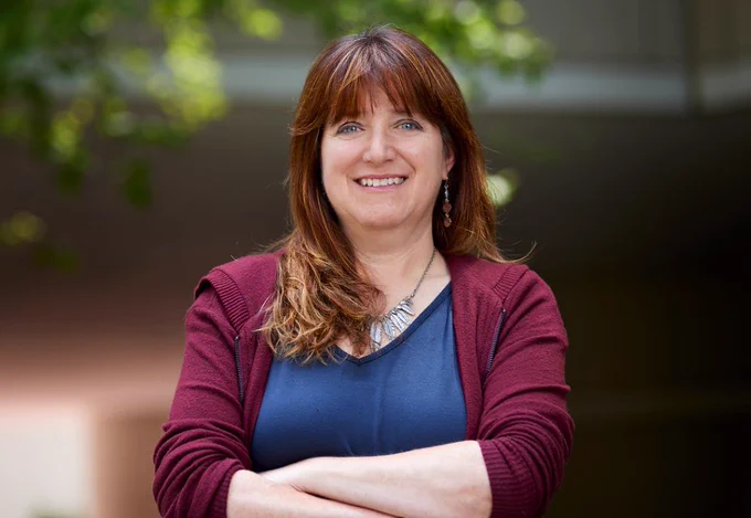 Scientist standing with her arms crossed in front of her.
