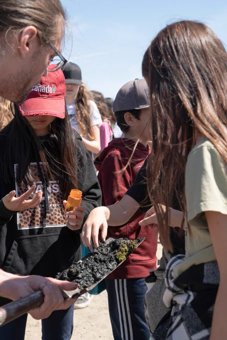 Students examining soil samples on a shovel.