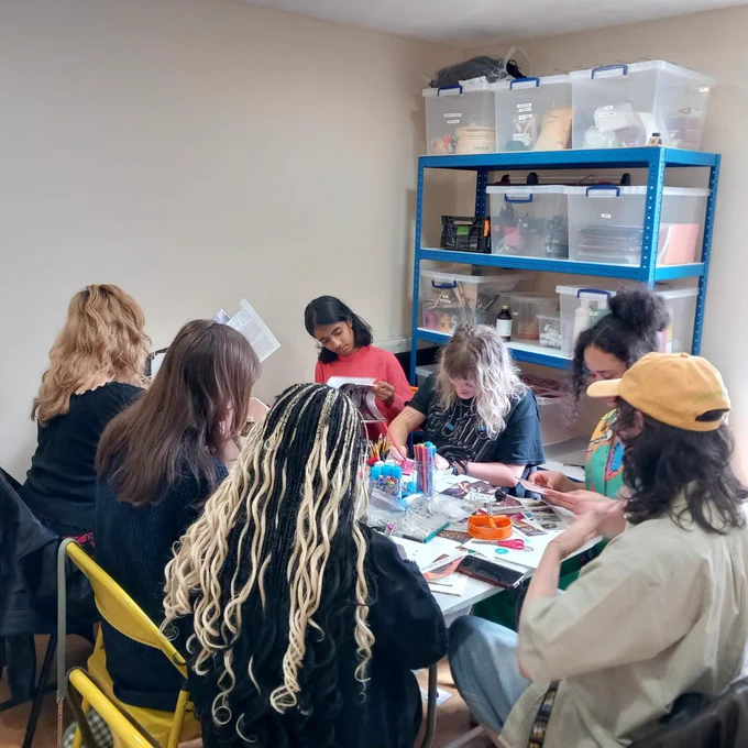 A group of people sitting round a table making zines
