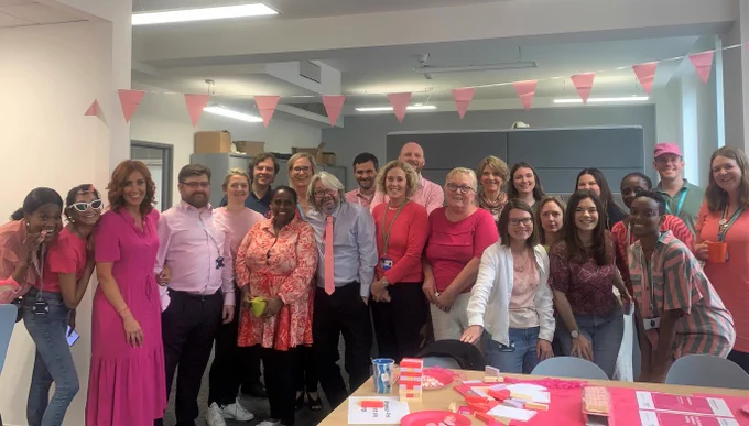 RCPCH staff wearing pink and smiling to camera at our pink themed tea party 