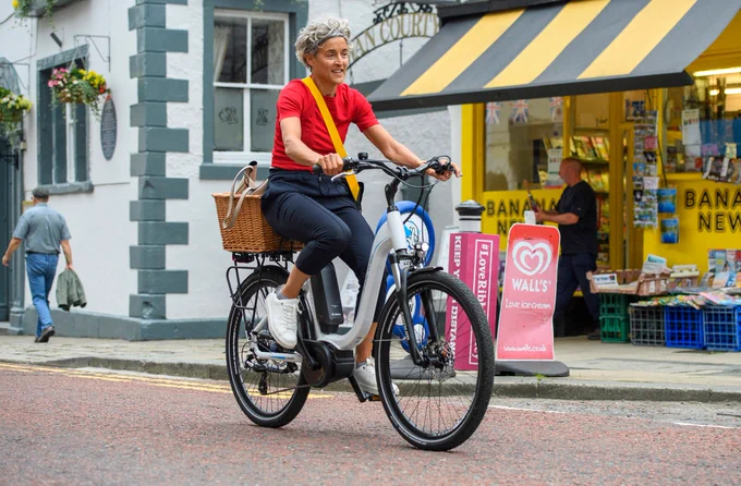 Person cycling on an e-bike along a high street