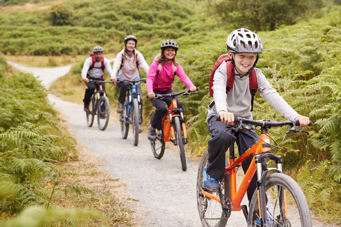 A group of young people riding bicycles outdoors.