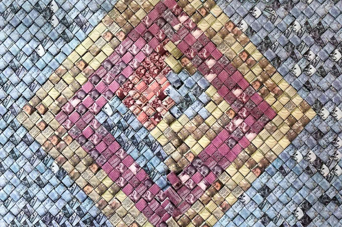 Currency in the colors of bluish gray, gold, rose, and orangey pink woven folded into squares and woven into the shape of diamonds