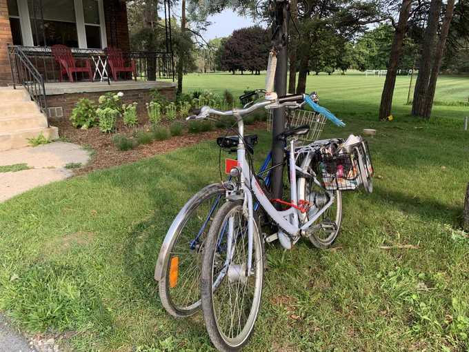 Two blue bicycles locked to a post