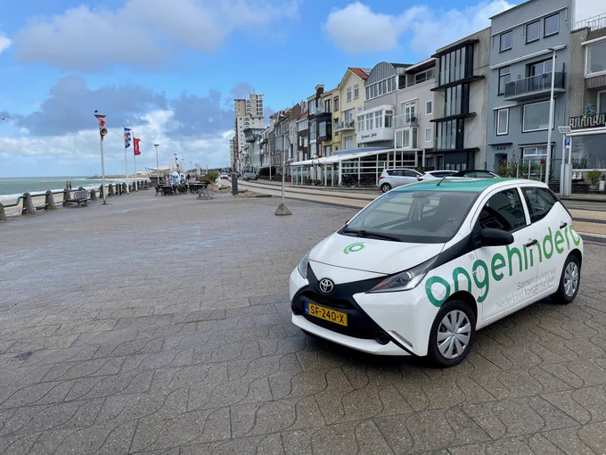 Foto van een Ongehinderd auto op de boulevard in Vlissingen, links het strand, rechts de huizen.