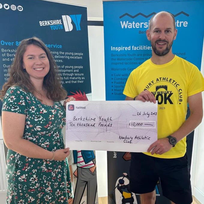 Photo of Berkshire Youth CEO, Sarah Emery, receiving large £10,000 cheque from Jeff Bird. Newbury Athletic Club Treasurer