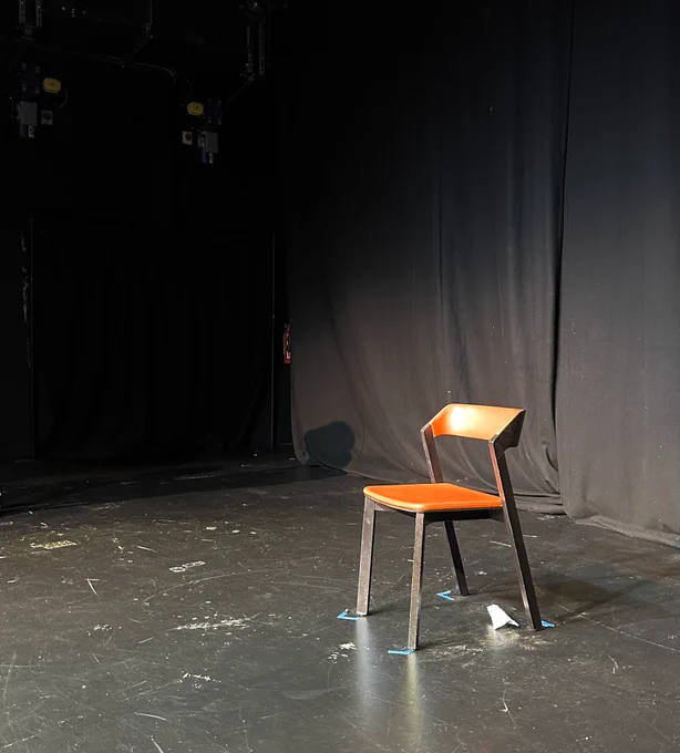 An orange chair in a rehearsal space.