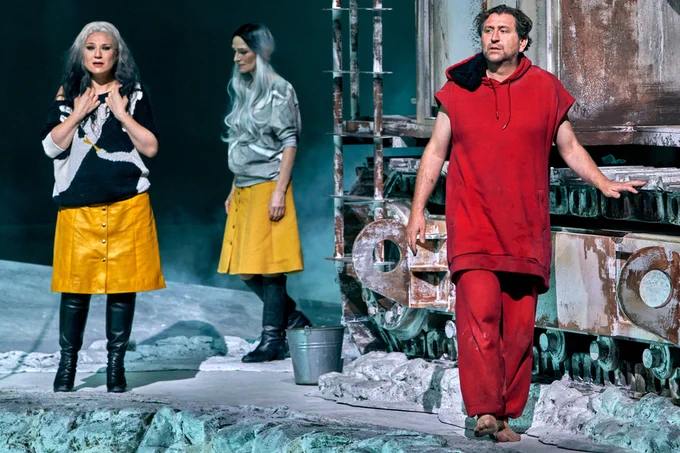 Three people are pictured: two women, wearing yellow skirts, and a man wearing all red.