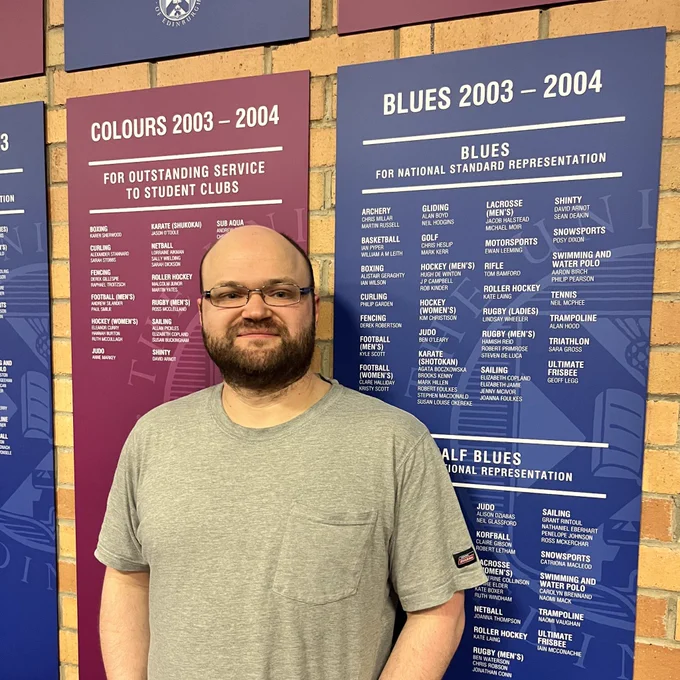 image of Blues and colours recipient in front of their award board at the Pleasance Gym