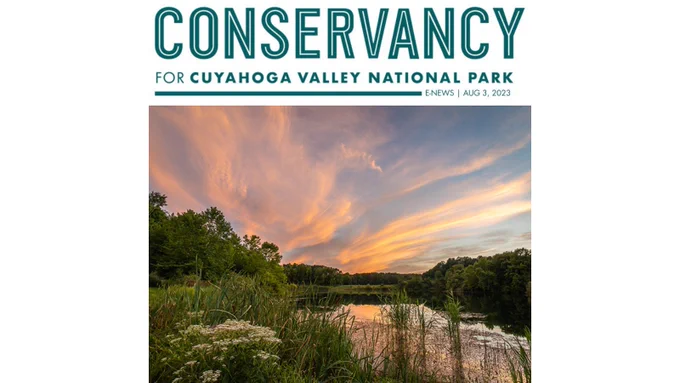 A photo of a colorful sunset over a small lake lined with trees and other plants. Above the photo is a logo for the Conservancy for Cuyahoga Valley National Park, the word E News and the date August 3, 2023. 