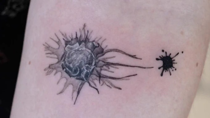 Black & white tattoo of a macrophage reaching towards a blob of ink.