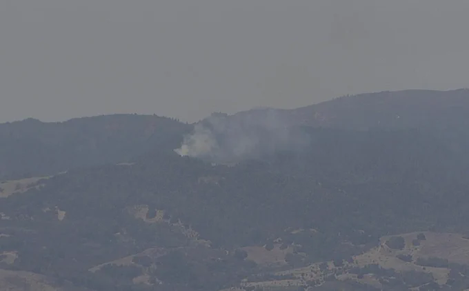 A screenshot of smoke from a vegetation fire on a hillside.