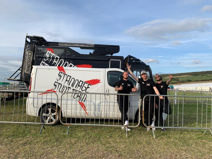Stunt team wave by their vehicle