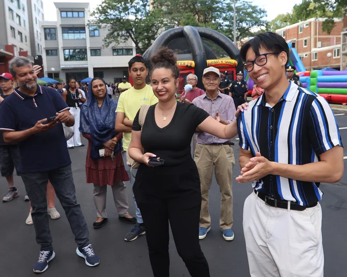 A crowd of people and a constituent with their hand on Chinatown, Leather District and Downtown Boston liaison Chulan Huang. 