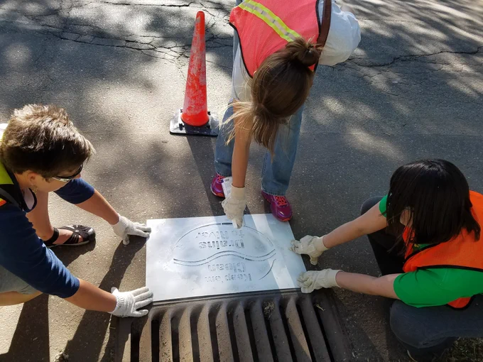 MPCA staff stenciling a storm drain