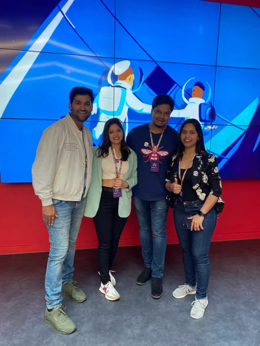 Picture of people Arpit Shrivastava and Manju Gurjar with their friends standing in front of a large TV screen at Scottish Summit
