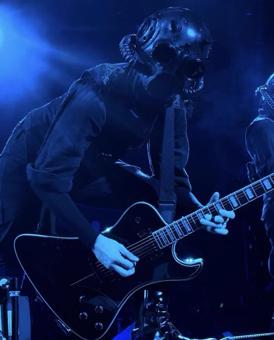 phantom ghoul leaning forward while playing guitar, dark blue lighting