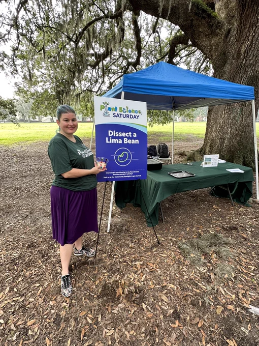 A smiling volunteer posed for a photo next to the Dissect a Lima Bean sign!