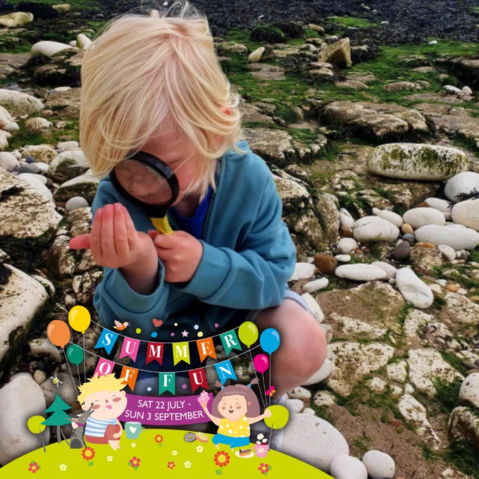 Child looking through magnifying glass on beach